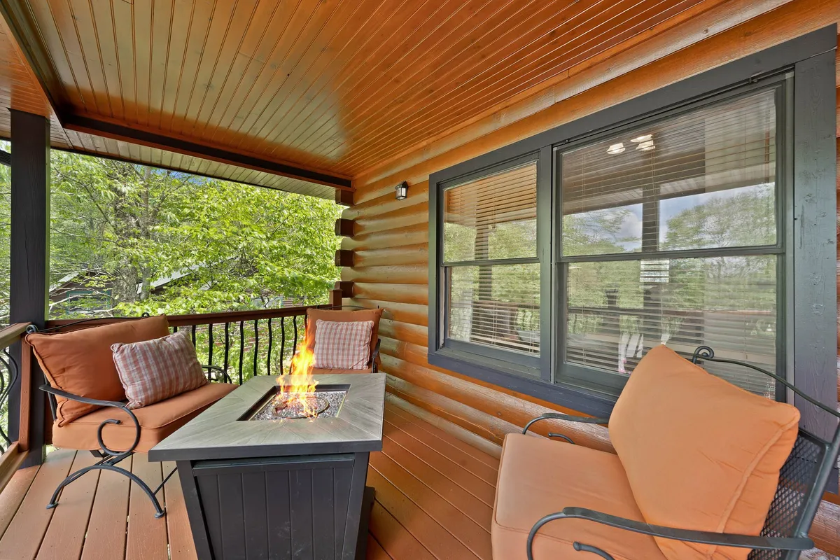 This image features a cozy fire pit surrounded by comfortable seating and large windows, blending indoor comfort with the ambiance of an outdoor gathering. The scene suggests warmth and togetherness, ideal for sharing stories and relaxing after a day out.