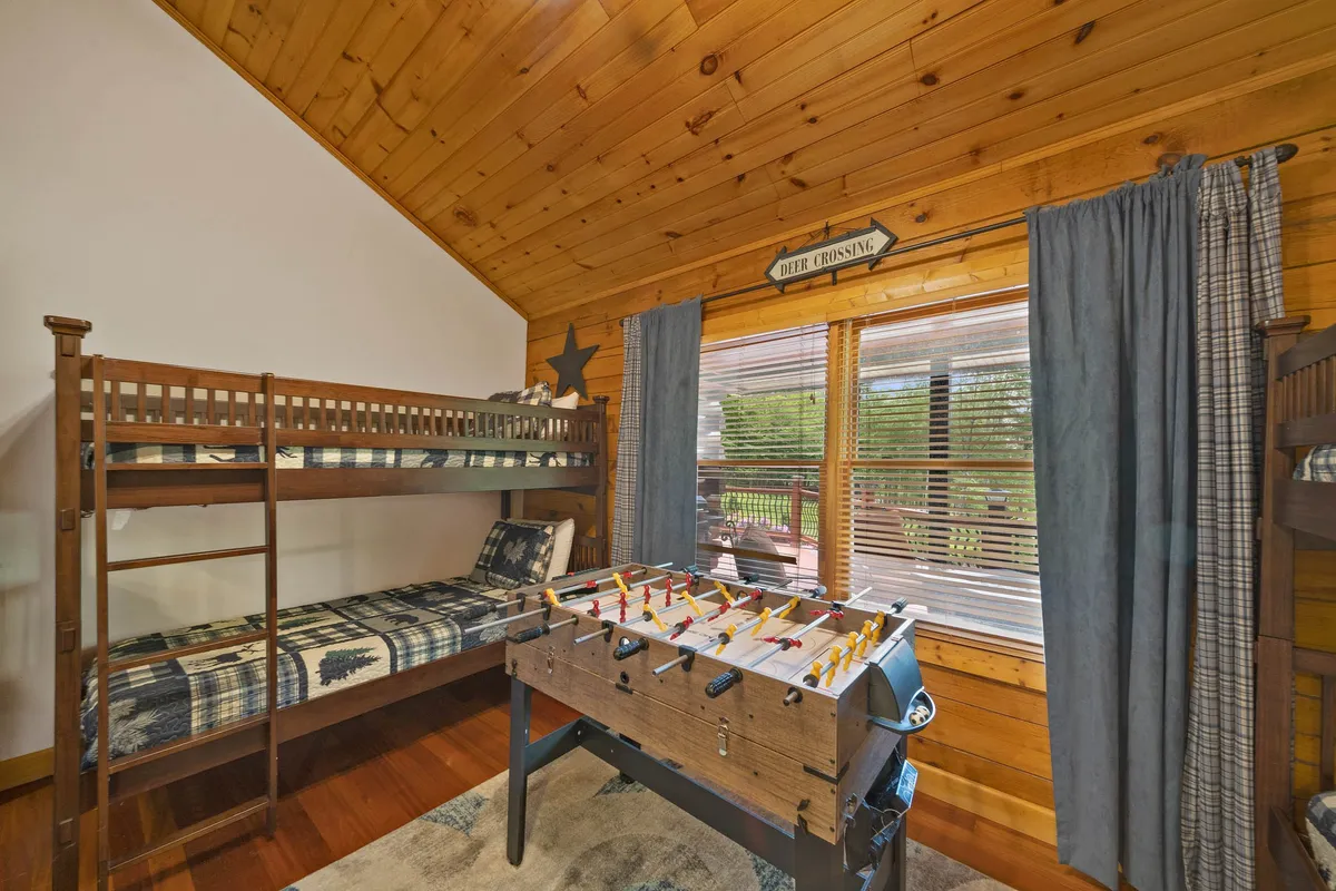 Another perspective of the family game room, featuring bunk beds and a foosball table near large windows, emphasizing activities like playing games, sleepovers, and relaxing with a scenic view.