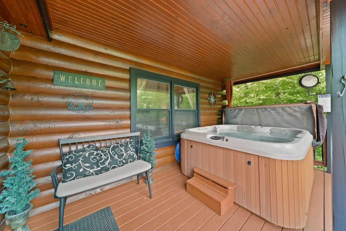 An inviting interior space looking out to nature, with a hot tub, cozy bench seating, and greenery both inside and just outside the screened area. The setup promises relaxing evenings with a direct visual connection to the outdoors.