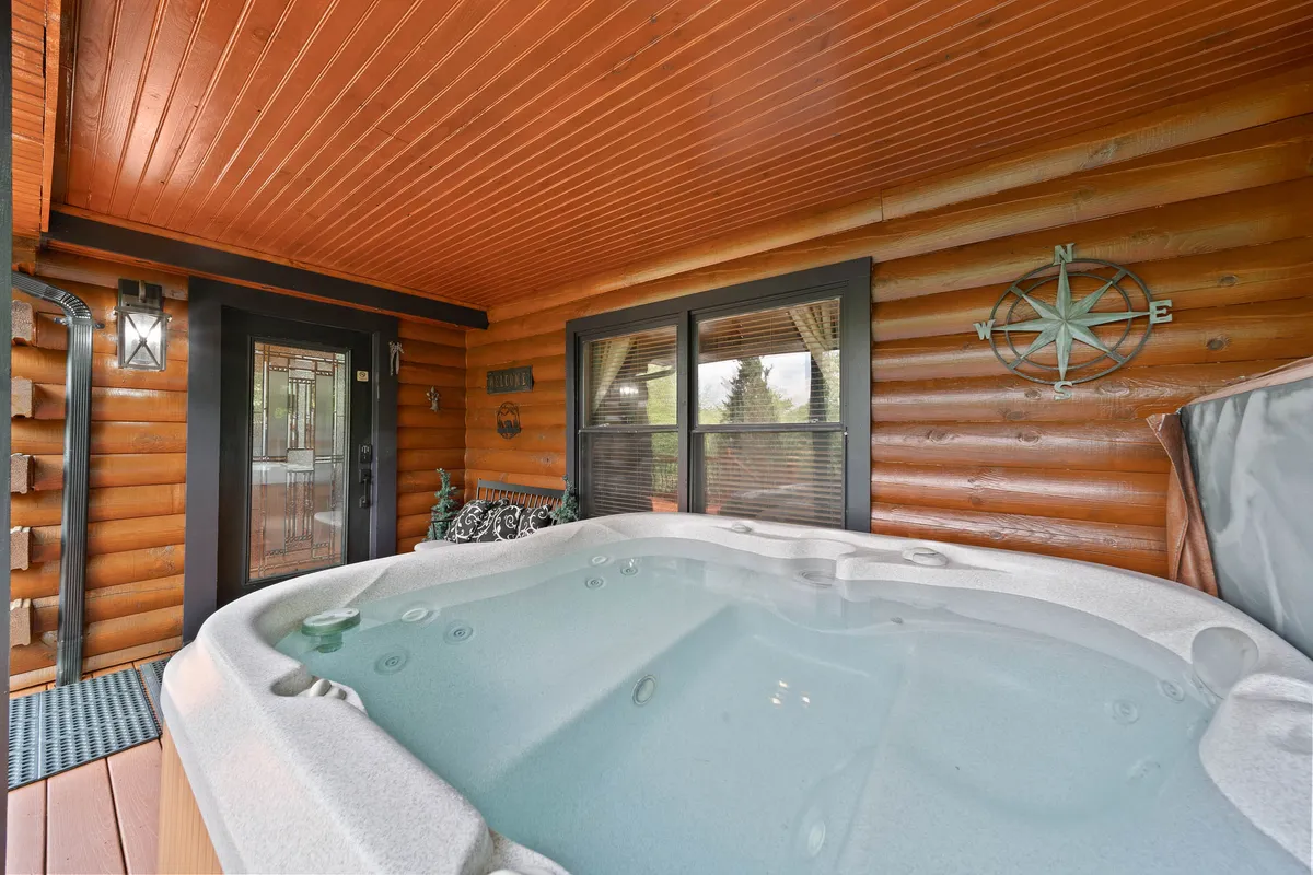 An inviting hot tub is set against warm wooden walls, with a window view hinting at the surrounding landscape. The tranquil space implies relaxation after a day outdoors.
