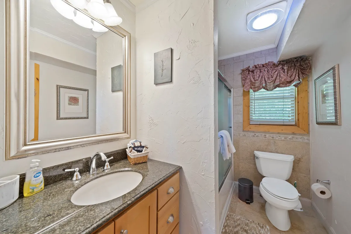 A bright bathroom with a vanity and mirror, a walk-in shower area, and a window that lets in soothing natural light. The space feels fresh, serene, and ideal for self-care routines or relaxing after outdoor activities.